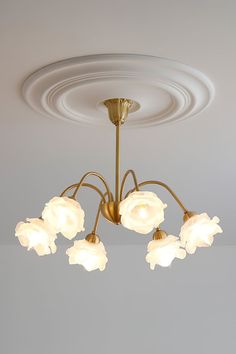 a chandelier with five white flowers hanging from it's center circle light fixture