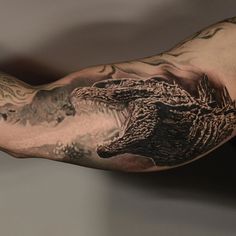 a man's arm with an alligator tattoo on it