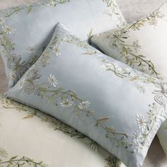 four pillows on top of each other with flowers and leaves in them, sitting on a bed