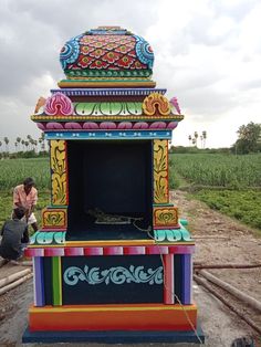 a colorfully painted cart sitting on the side of a road next to a field