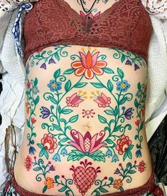 a woman's stomach is decorated with flowers and leaves, while wearing a bra