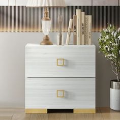 a white and gold chest of drawers next to a vase with flowers in it on a wooden floor