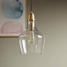 a clear glass light hanging from a ceiling fixture in a room with a painting on the wall