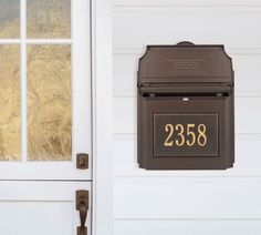 a brown mailbox sitting on the side of a white door