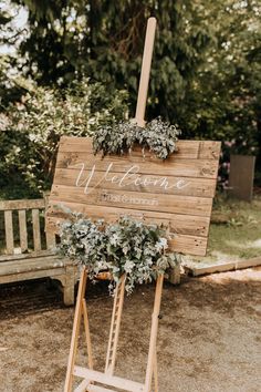 a wooden welcome sign with greenery on it