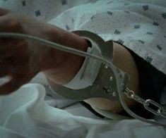 a person in a hospital bed with handcuffs around their ankles