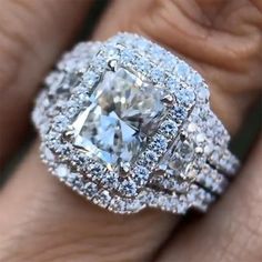 a woman's engagement ring with an assorted diamond surrounded by smaller round diamonds