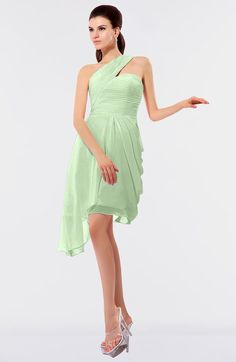 a woman in a short green dress is posing for the camera with her hand on her hip