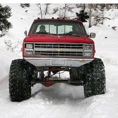 a red truck driving through the snow on top of it's tire arches and tires