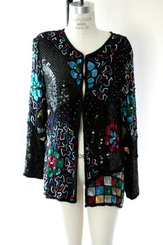 "Beautifully beaded Sequin Jacket. I love the colors on this one!! Turquoise, greens, reds, pearl beaded..a real beauty. The tags were taken out of this, so I am putting the size at a medium because of the measurements. This jacket is in Very good condition, I do not see any flaws..and the colors are so beautiful!! This is on silk and lined in rayon. There are hooks up and down the front, (they are all there) so this can be used as a blouse or an open jacket. Measuring: 27\" length Width: 40\" S Festive Fitted Beaded Outerwear, Beaded Fall Festive Outerwear, Long Sleeve Embellished Outerwear For Party, Festive Beaded Fall Outerwear, Vintage Beaded Outerwear For Spring, Beaded Vintage Outerwear For Spring, Spring Vintage Beaded Outerwear, Multicolor Embellished Outerwear For Winter, Spring Beaded Outerwear For Parties