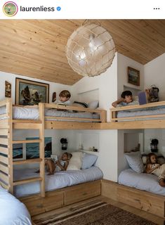 three children are laying on bunk beds in a room with wood ceilinging and white walls