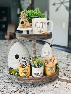 two tiered tray with coffee mugs and honey jars on top of a kitchen counter