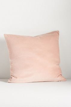 a pink pillow sitting on top of a white bed