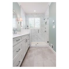 a large bathroom with white cabinets and marble counter tops, along with a walk in shower