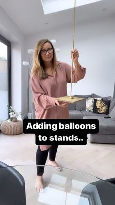 a woman standing in front of a glass table holding an object with the words adding balloons to stands