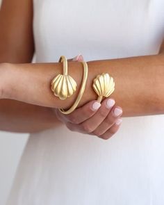 Wrap your wrist with one of the most coveted styles from the late 60s and 70s. Inspired by fabulous women and their best accessories, our Marbella Wrap Bangle is all you need to dress up your every day. Unique in shape and lightweight to wear, it’s the perfect piece to jazz up your jewelry box. Looking closely, you’ll notice that the textured look of the band comes from an intricate design of small diamond-shaped indentations. Made complete with the Marbella Shell pendant at each end, this brace Adjustable Formal Jewelry For Summer, Adjustable Summer Formal Jewelry, Retro Jewelry For Parties, Chic Evening Bracelets, Chic Formal Bracelets With Oyster Detail, Chic Bracelets For Spring Parties, Gold Bracelet For Formal Occasions In Spring, Formal Gold Bracelet For Spring, Gold Vintage Jewelry For Spring