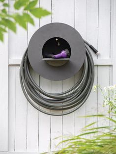 a garden hose holder attached to the side of a white fence