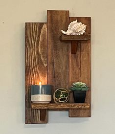 a wooden shelf with two candles on it and some succulents next to it