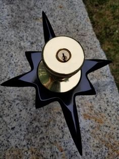 a black and white star shaped object sitting on top of a cement slab next to grass