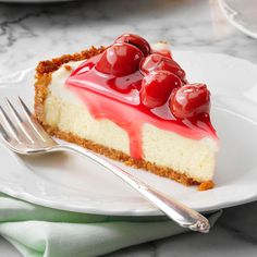 a piece of cheesecake with cherries on top is sitting on a white plate