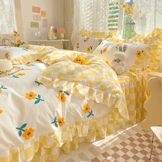 a bed with yellow and white bedspreads in a bedroom next to a window