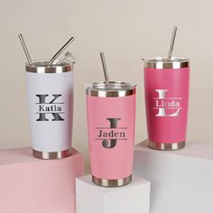 three different colored tumblers with straws in them on a pink and white surface