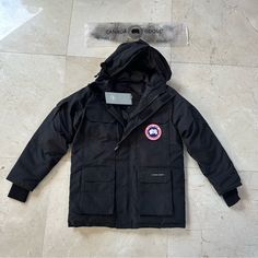 Stay Warm And Comfortable This Winter With The Canada Goose Expedition Heritage Parka In Black. This Parka Is Made With Durable Polyester And Lined With Soft Nylon To Keep You Cozy During Cold Weather. The Parka Features A Solid Pattern With Fur Trim And A Full Zipper Closure To Keep The Cold Out. The Parka Is Water-Resistant, Insulated With Down, And Breathable, Making It Perfect For Outdoor Activities Like Hiking And Walking. It Also Has Reflective Features For Added Visibility And Safety. Thi Canada Goose Mens, Solid Pattern, Black Media, Fur Trim, Canada Goose, Canada Goose Jackets, Stay Warm, Cold Weather, Outdoor Activities