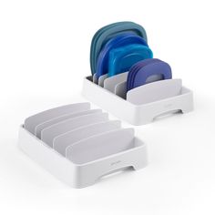 two white dishes and one blue dish are stacked in the holder for each other on a white background