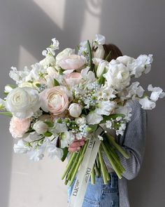 a woman holding a bouquet of white and pink flowers in her hands with a ribbon around her waist