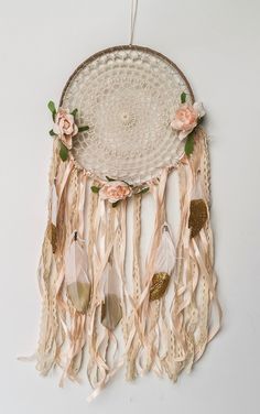 a dream catcher with flowers and feathers hanging from it's side on a wall