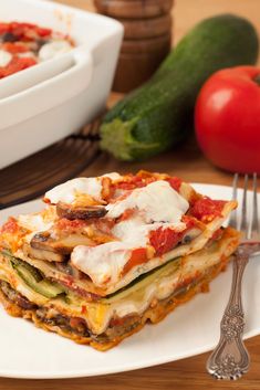 a white plate topped with lasagna covered in cheese and sauce next to a fork