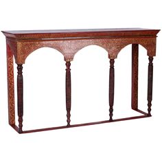 an ornate wooden console table with intricate carvings on the top and sides, along with two columns