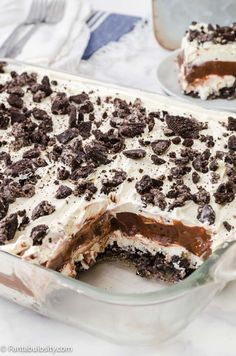 a chocolate dessert with white frosting and oreo cookies on top in a glass dish