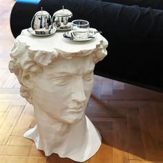 a white sculpture with cups and saucers sitting on top of it's head