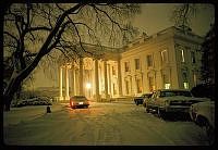 cars parked in front of a large building with columns on it's sides at night