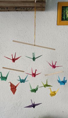 origami birds hanging from clothes pins on a string in front of a white wall