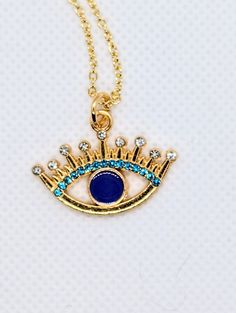 Gold evil eye necklace with blue and white cubic zirconia. Gold tone necklace is 18" in length and is adjustable. Blue Necklace With Adjustable Length For Gifts, Blue Charm Necklace With Adjustable Chain, Blue Evil Eye Charm Necklace, Evil Eye Pendant Necklace In Cubic Zirconia, Blue Necklaces With Diamond Eyes As Gift, Blue Necklace With Diamond Eyes As Gift, Gold Evil Eye Necklace, Evil Eye Necklace Gold, Evil Eye Necklace