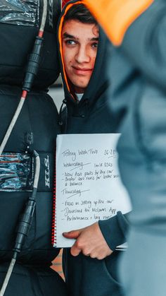 a young man holding a piece of paper with writing on it in front of him