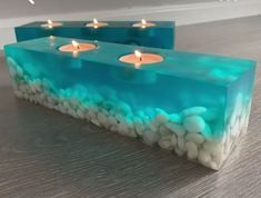 two candles that are sitting on some kind of block with rocks and pebbles in it