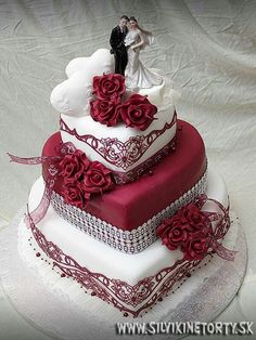 a red and white wedding cake with roses on it