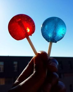 two colorful lollipops being held in front of a building with the sun shining on them