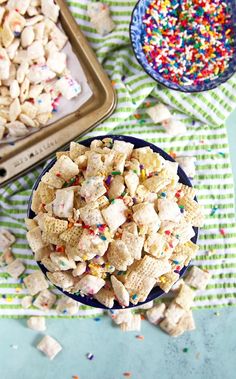 a blue bowl filled with cereal and sprinkles next to a cookie sheet