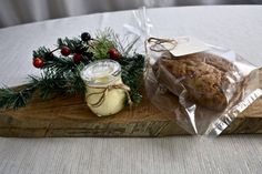 a wooden cutting board topped with cookies next to a jar of jelly and pine cones