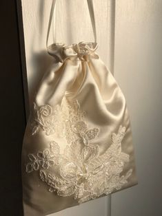 a white satin bag hanging from a door with lace on the front and back of it