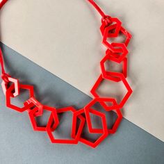 A bright red geometric mid-length chunky perspex necklace.  My necklaces are light and easy to wear and will give your favourite outfit an instant pop of colour. Unique Valentine present all wrapped ready for gifting! Designed using twelve laser cut perpsex shapes linked together the necklace is 24 inches long with a drop of 12 inches. There are 4 large, 4 medium and 4 small shapes measuring 2, 1.5 and 1 inch wide each. Finished with silky red cord and a silver plated magnetic clasp. This clasp Modern Red Necklace For Party, Red Plastic Party Jewelry, Trendy Red Plastic Jewelry, Contemporary Red Jewelry For Gift, Cheap Red Statement Necklace, Unique Red Necklace With Large Pendant, Modern Red Geometric Jewelry, Luxury Red Modernist Jewelry, Acrylic Necklace