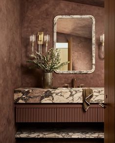 a bathroom with marble counter tops and gold accents on the walls, along with a large mirror