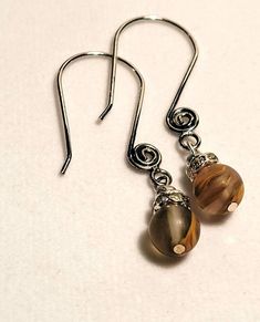 These earrings are made with unique and stunning agate beads. When the stones catch the light they are brilliant browns with hints of yellow, orange, and black.  The stones are highlighted by Swarovski crystal beads and decorative silver earwires. Nickel Free Brown Earrings With Czech Glass, Elegant Teardrop Beaded Earrings In Brown, Elegant Brown Teardrop Beaded Earrings, Brown Wire Wrapped Drop Beaded Earrings, Brown Wire Wrapped Drop Earrings, Brown Earrings With Natural Stones And Round Beads, Brown Teardrop Czech Glass Jewelry, Elegant Brown Czech Glass Earrings, Brown Czech Glass Teardrop Jewelry