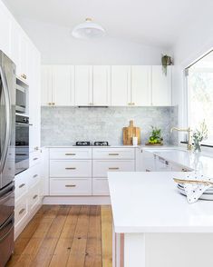 a kitchen with white cabinets and wood floors