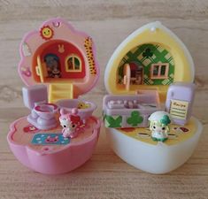 two little toys are sitting on the table next to each other, one has a doll house in it