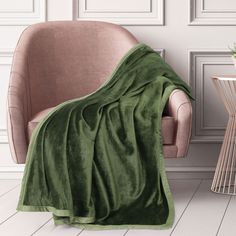 a green blanket sitting on top of a chair next to a potted plant